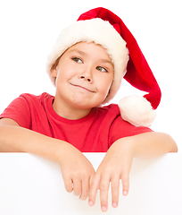 Image showing Little girl in santa hat is holding blank board