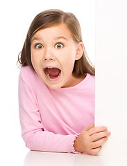 Image showing Little girl is looking out from the blank banner