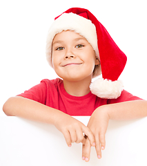 Image showing Little girl in santa hat is holding blank board