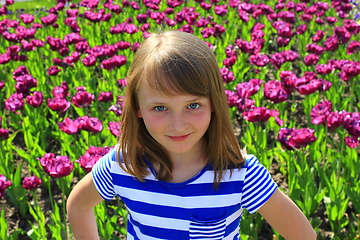 Image showing little girl stand by lilac tulips