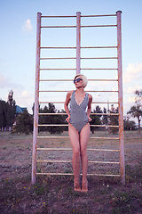 Image showing Beautiful woman in black and white striped swimsuit on the old sports ground. Film effect.