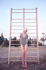 Image showing Beautiful woman in black and white striped swimsuit on the old sports ground. Film effect.