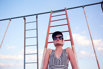 Image showing Beautiful woman in black and white striped swimsuit on the old sports ground. Film effect.