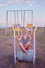 Image showing Beautiful woman in black and white striped swimsuit on the old sports ground. Film effect.