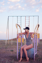 Image showing Beautiful woman in black and white striped swimsuit on the old sports ground. Film effect.