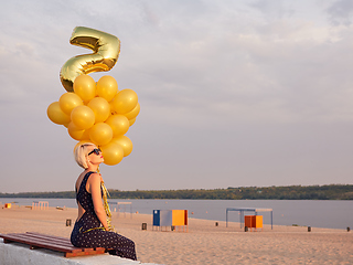 Image showing Young woman with many golden balloons.