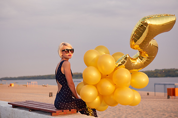 Image showing Young woman with many golden balloons.