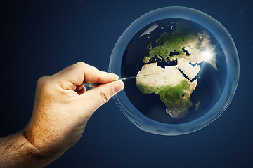 Image showing Planet earth in a soap bubble and a hand with a needle that burs