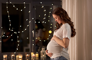 Image showing happy pregnant woman looking out window at home