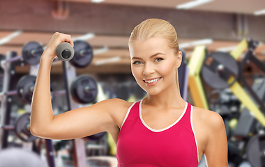 Image showing happy young woman with dumbbells exercising in gym