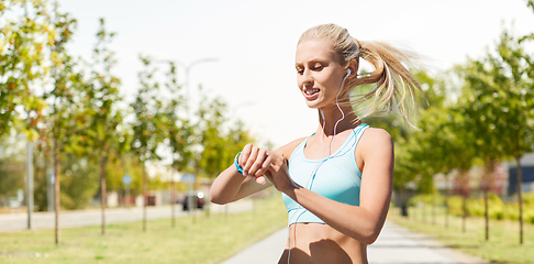 Image showing happy woman with fitness tracker and earphones