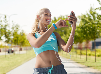 Image showing happy woman with smartphone and earphones outdoors