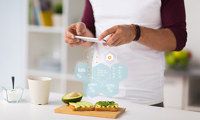 Image showing hands with phone and food nutritional value chart