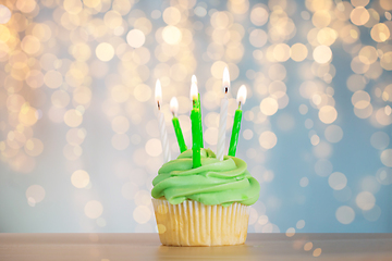 Image showing green cupcake with six burning candles on table