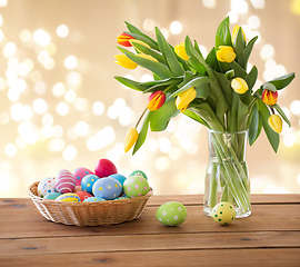 Image showing colored easter eggs in basket and tulip flowers