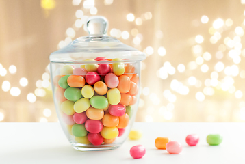 Image showing glass jar with candy drops over lights background