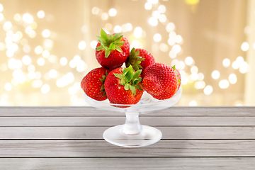Image showing strawberries on glass stand over lights background