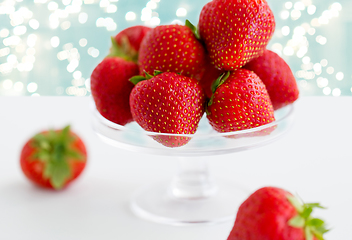 Image showing strawberries on glass stand over white background