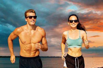 Image showing couple with earphones running over sea