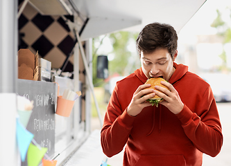 Image showing hungry young man eating hamburger at food truck