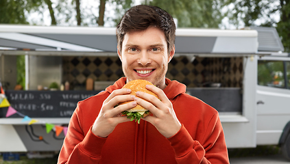 Image showing happy young man eating hamburger at food truck