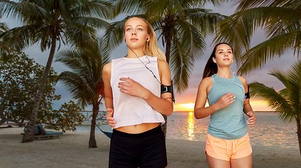 Image showing young women with earphones and smartphones running