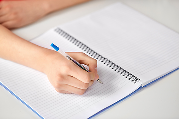 Image showing hands of student girl with pen writing to notebook