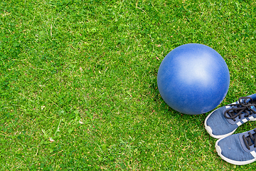 Image showing Fitness ball and sneakers on the green grass background