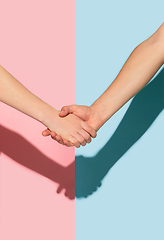 Image showing Female and male hands holding on pink and blue background