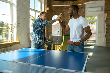 Image showing Young men playing table tennis in workplace, having fun