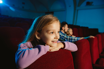 Image showing Young caucasian family watching a film at a movie theater