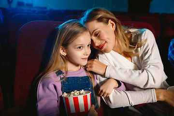 Image showing Young caucasian mother and daughter watching a film at a movie theater