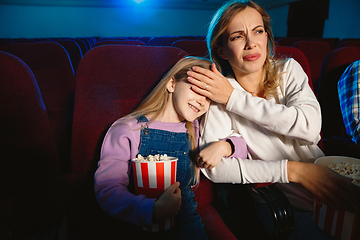 Image showing Young caucasian mother and daughter watching a film at a movie theater