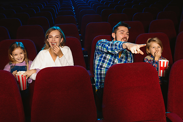 Image showing Young caucasian family watching a film at a movie theater