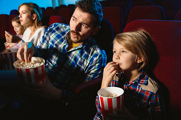 Image showing Young caucasian family watching a film at a movie theater