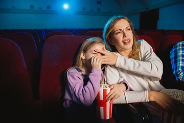 Image showing Young caucasian mother and daughter watching a film at a movie theater