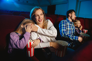 Image showing Young caucasian family watching a film at a movie theater