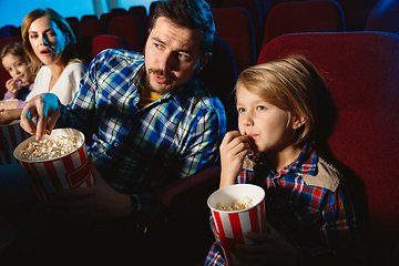 Image showing Young caucasian family watching a film at a movie theater