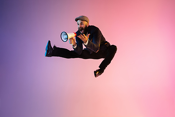 Image showing Full length portrait of happy jumping man in neon light and gradient background