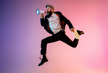 Image showing Full length portrait of happy jumping man in neon light and gradient background