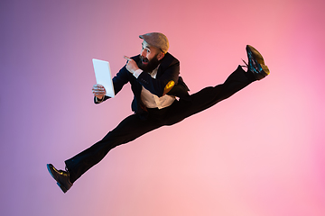 Image showing Full length portrait of happy jumping man in neon light and gradient background