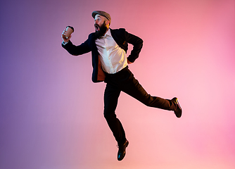 Image showing Full length portrait of happy jumping man in neon light and gradient background