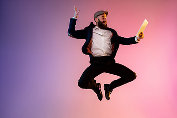 Image showing Full length portrait of happy jumping man in neon light and gradient background