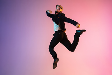 Image showing Full length portrait of happy jumping man in neon light and gradient background