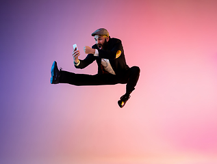 Image showing Full length portrait of happy jumping man in neon light and gradient background