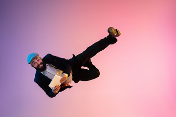 Image showing Full length portrait of happy jumping man in neon light and gradient background