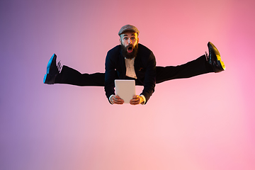 Image showing Full length portrait of happy jumping man in neon light and gradient background