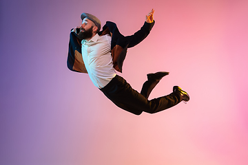 Image showing Full length portrait of happy jumping man in neon light and gradient background