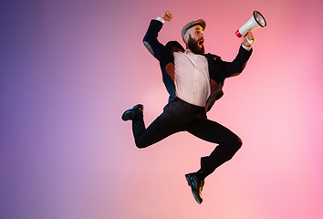 Image showing Full length portrait of happy jumping man in neon light and gradient background