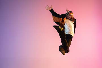 Image showing Full length portrait of happy jumping man in neon light and gradient background